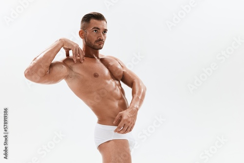 Man athletic body bodybuilder in briefs with naked torso abs full-length in the background  fitness classes. Advertising  sports  active lifestyle  competition  challenge concept.