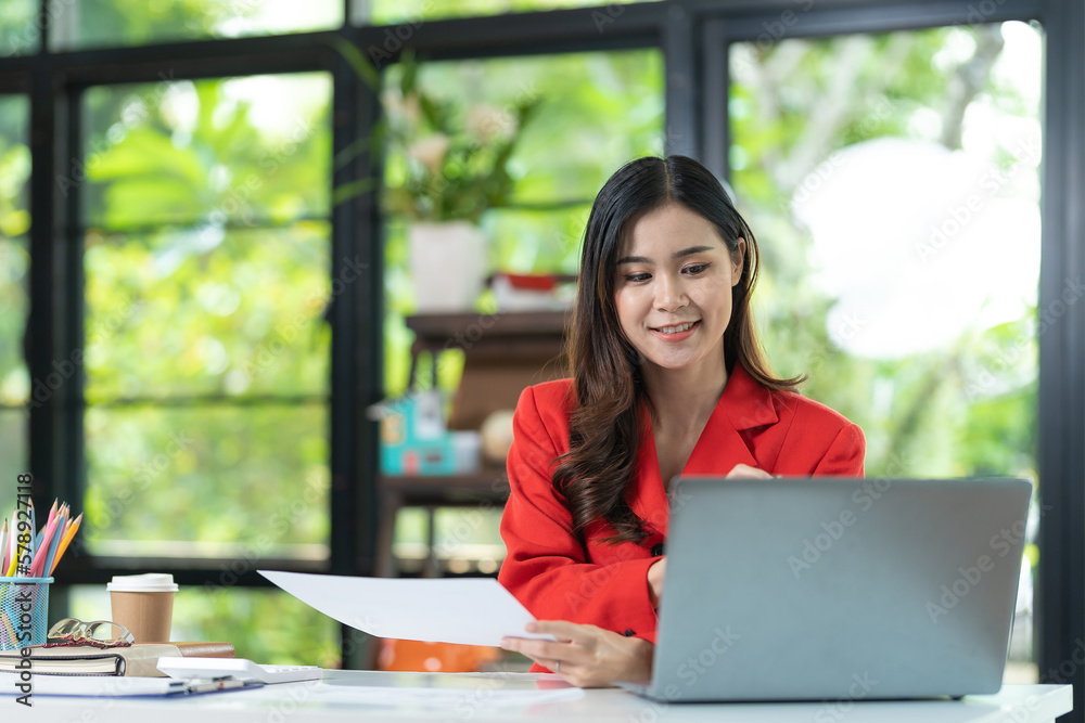 Portrait of pretty cheerful girl smiling while working on laptop in office