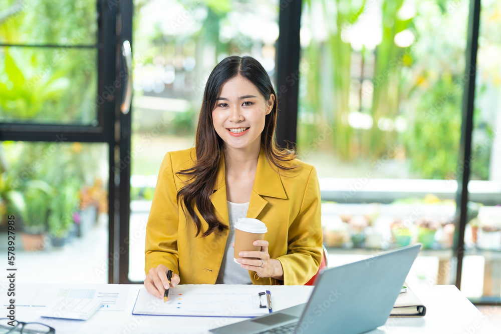 Young minded successful employee business woman in yellow shirt work hold takeaway delivery craft paper cup coffee sitting at desk with laptop pc computer at office indoor achievement career concept Young minded successful employee business woman in yellow shirt work hold takeaway delivery craft paper cup coffee sitting at desk with laptop pc computer at office indoor achievement career concept