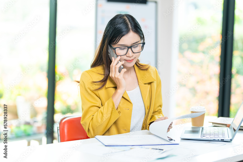 Happy business woman talking on mobile phone while analyzing weekly schedule in her notebook Happy business woman talking on mobile phone while analyzing weekly schedule in her notebook