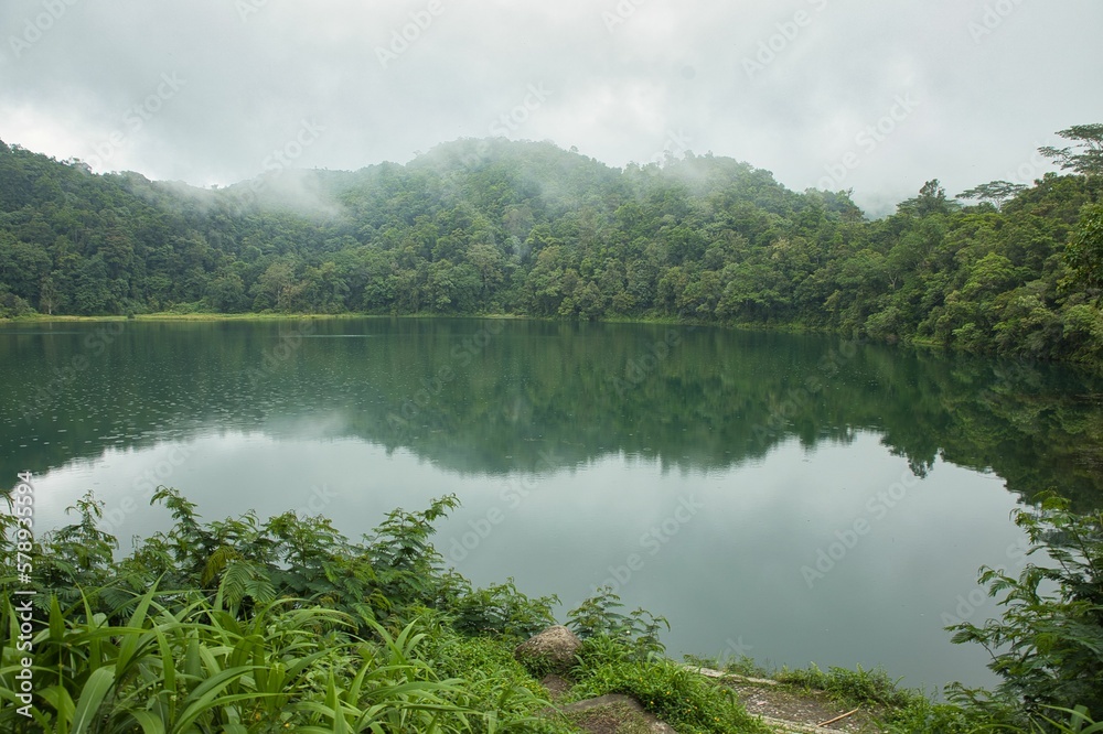 Idyllic shot of the green Rana Mese lake on Flores, surrounded by rainforest with hazy clouds. Idyllic shot of the green Rana Mese lake on Flores, surrounded by rainforest with hazy clouds.