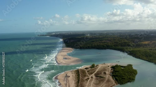 Dolly out aerial drone wide shot of the beautiful coastline of Gramame where the ocean meets the river near the tropical beach capital city of Joao Pessoa in Paraiba, Brazil on a warm summer day. photo