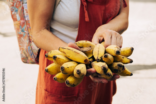 Manos de mujer con racimo de pequeñas bananas