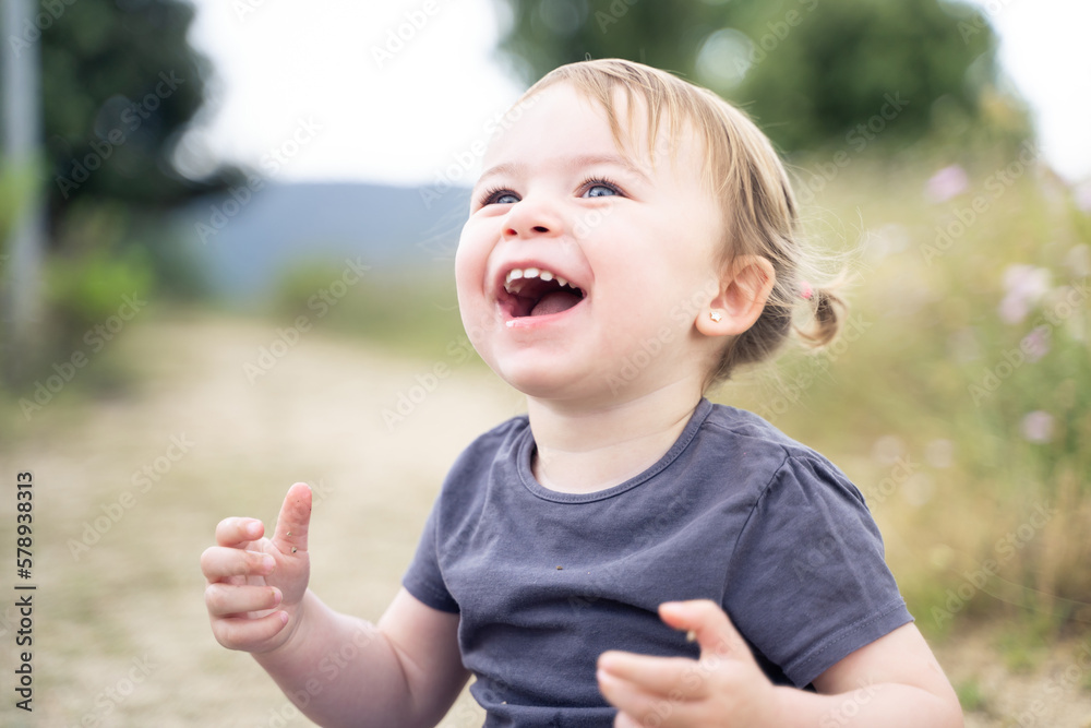 Little girl laughing with standing next to a rural path Little girl laughing with standing next to a rural path