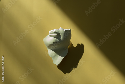 A fragment of an antique sculpture, a piece of a face on a yellow background.
