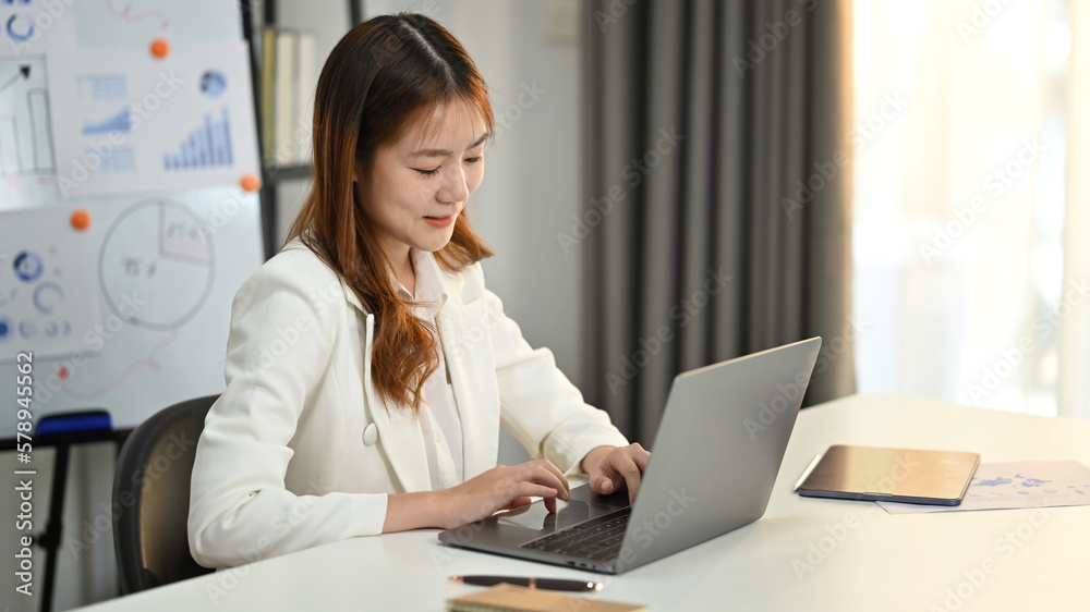 Charming young woman economist checking financial documents, working with statistics at her office desk Charming young woman economist checking financial documents, working with statistics at her office desk