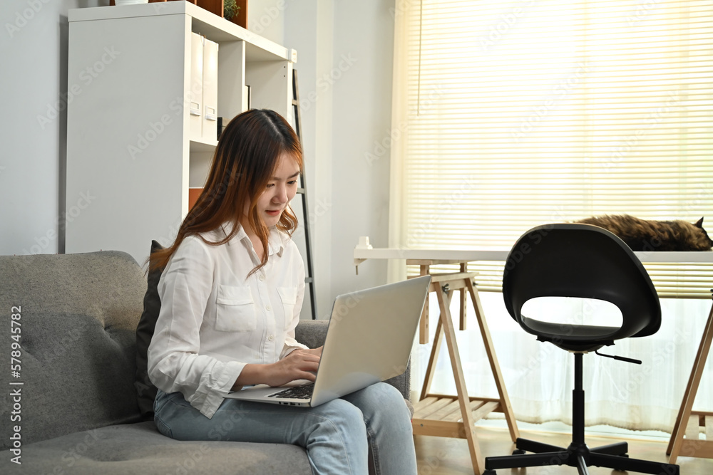 Young asian woman reading news online, checking social media on laptop at home. People, technology and lifestyle concept Young asian woman reading news online, checking social media on laptop at home. People, technology and lifestyle concept