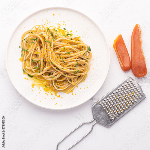 Spaghetti pasta with bottarga (dried tuna or mullet caviar) on a white table. Classic sea dish of Sardinia and Sicily islands. Italian healthy cuisine, square crop photo