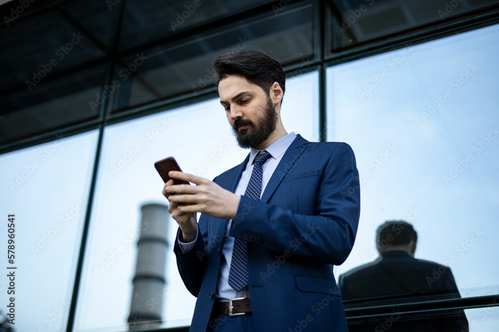 A handsome young business man is standing outside the building A handsome young business man is standing outside the building