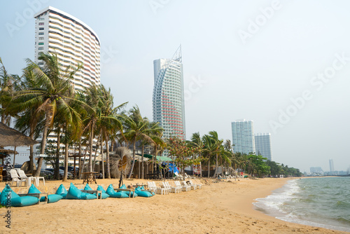 Seats and hotel on the beach with row of coconut trees for tourist to walk on holiday at Pataya beach,Thailand.