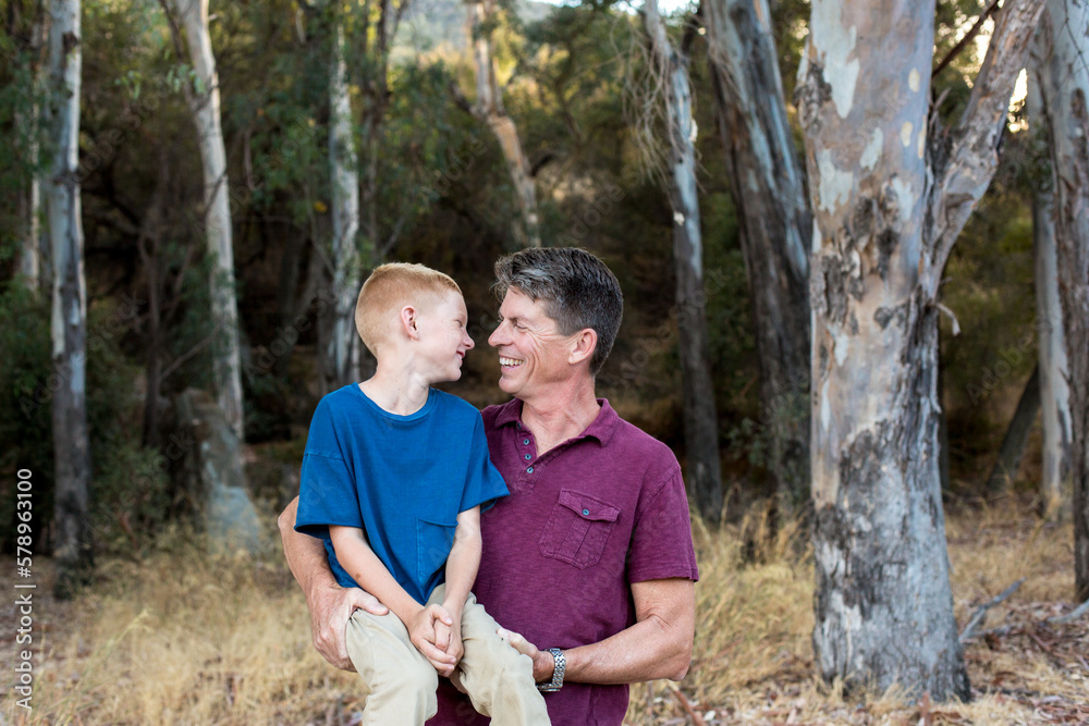Father holds son in a seated position and they smile at each other
