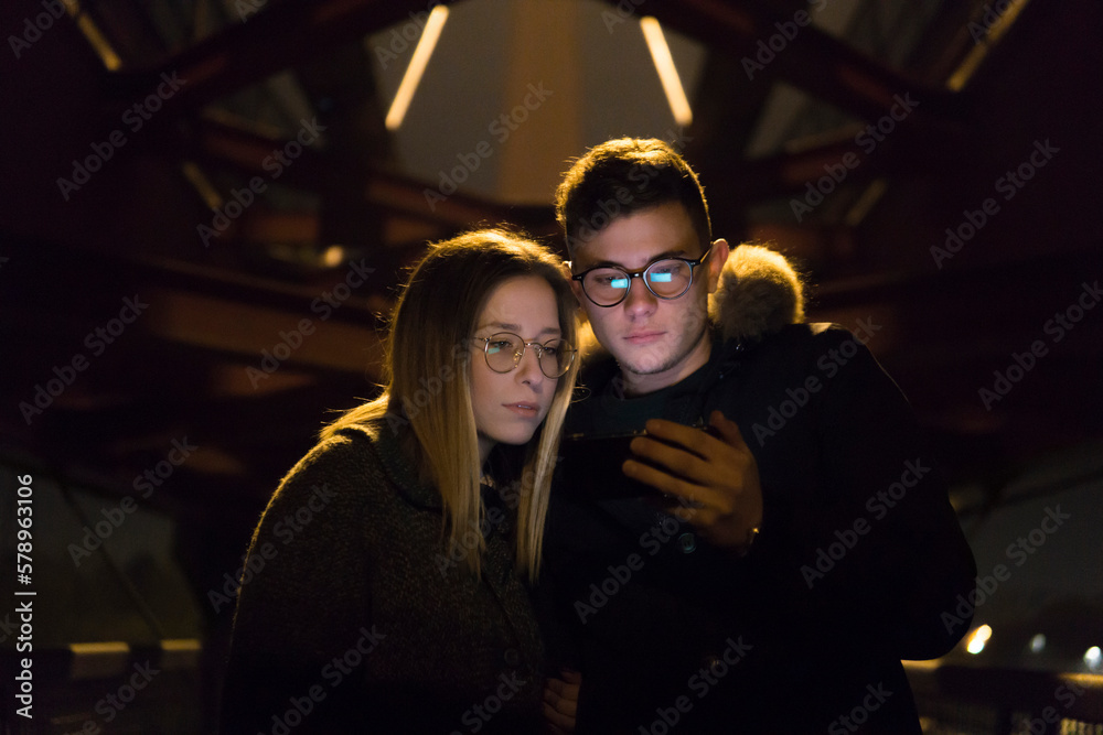 Couple Looking At Mobile Phone under a metal bridge Couple Looking At Mobile Phone under a metal bridge