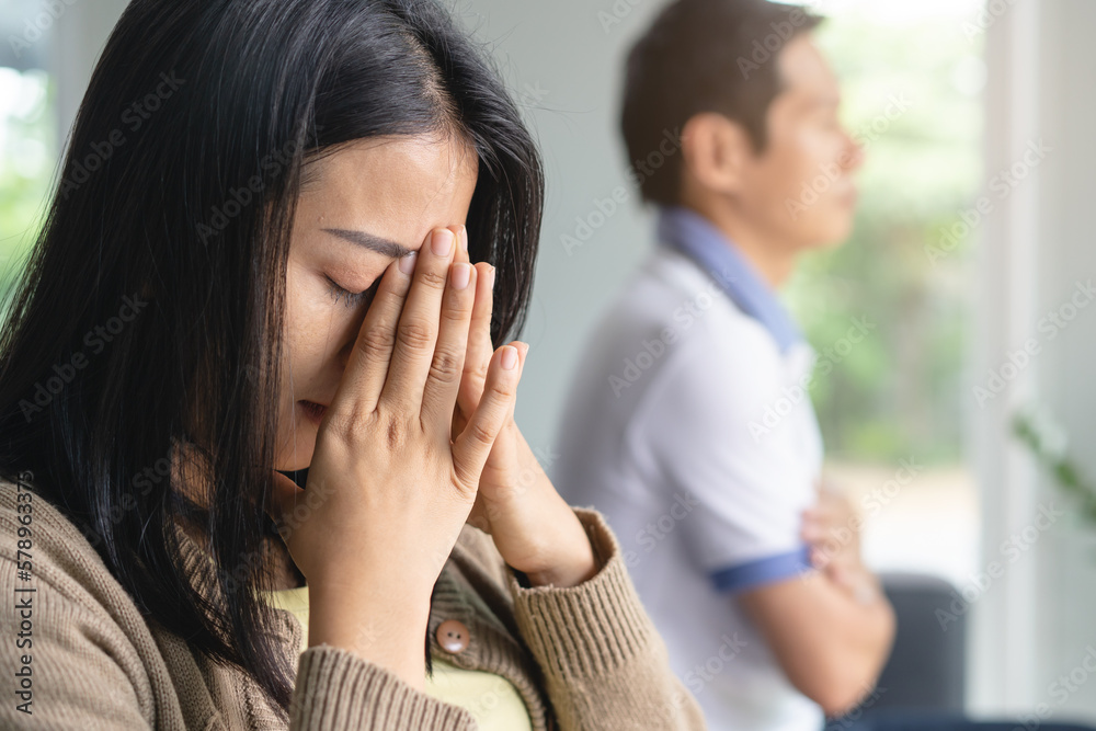 Asian couple having relation problem. Wife crying and sitting separate with her husband at home after quarrel. Asian couple having relation problem. Wife crying and sitting separate with her husband at home after quarrel.