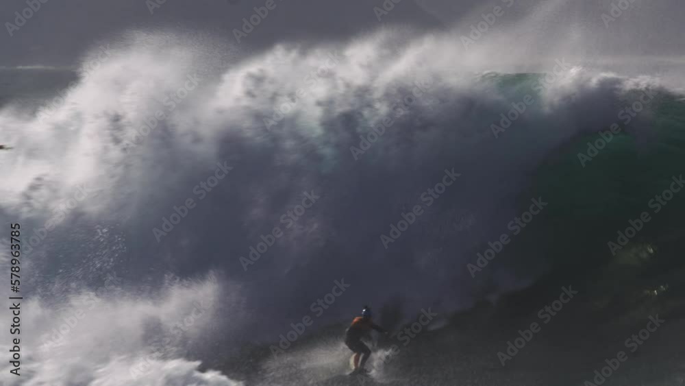 Surfer on a surfboard in the middle of big wild foamy waves. Dramatic shot Surfer on a surfboard in the middle of big wild foamy waves. Dramatic shot