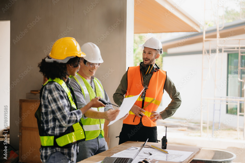 Contractor and architect looking at plan, tablet, laptop and talking about working on big project. Building in construction process interior. team work . Contractor and architect looking at plan, tablet, laptop and talking about working on big project. Building in construction process interior. team work .