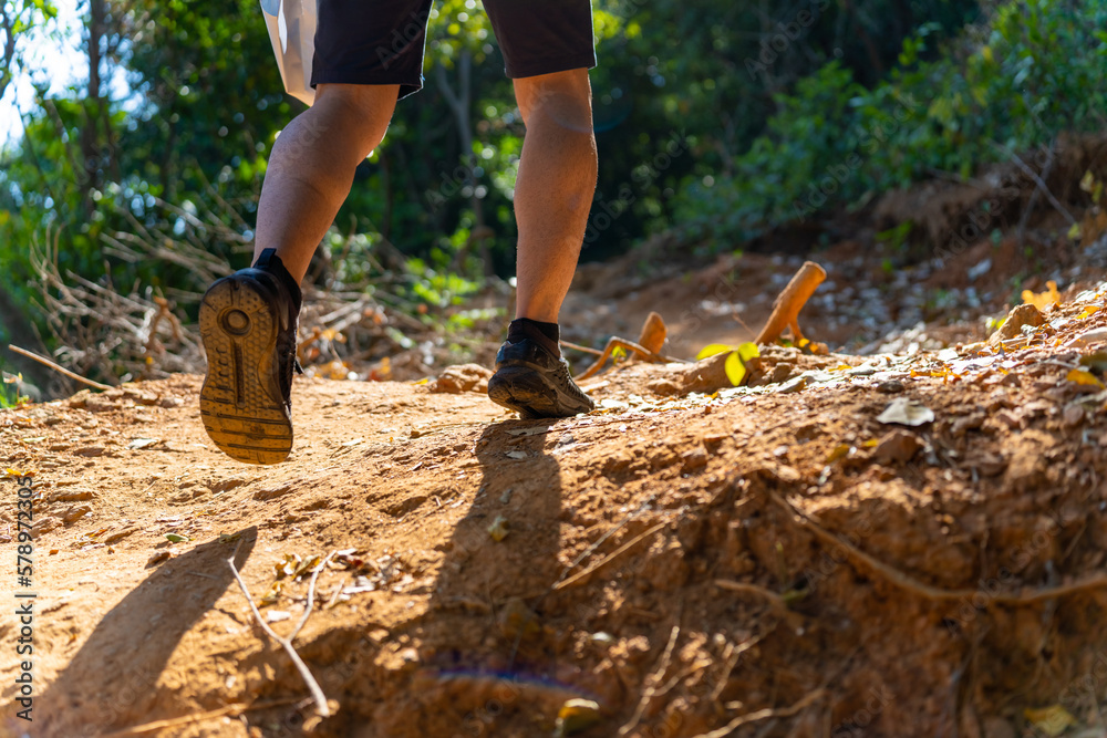 Caucasian man leg hiking on mountain hill in sunny day. Handsome guy enjoy adventure outdoor lifestyle walking on mountain dirt road on summer vacation. Ecotourism and solo travel concept. Caucasian man leg hiking on mountain hill in sunny day. Handsome guy enjoy adventure outdoor lifestyle walking on mountain dirt road on summer vacation. Ecotourism and solo travel concept.