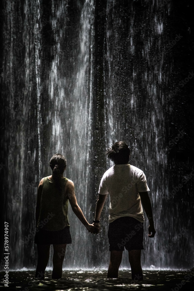 Young couple is at the beautiful waterfall, Bali, Indonesia