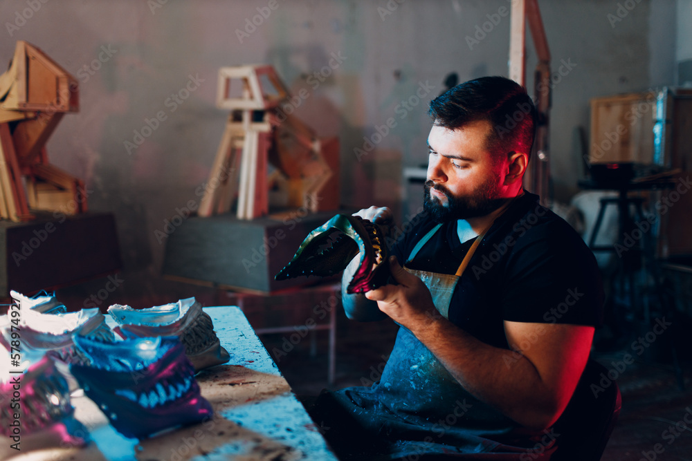 Fototapeta premium Artisan craftsman create mask based on plaster cast. Gypsum mold and plastic mask sculpting cutting knife
