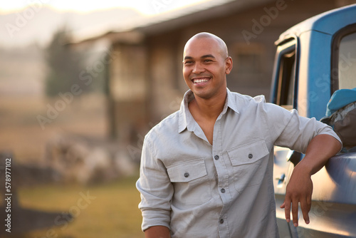 Portrait Of Man Loading Backpack Into Pick Up Truck For Road Trip To Cabin In Countryside
