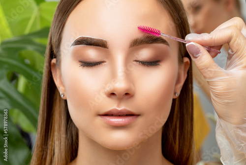 The make-up artist does Long-lasting styling of the eyebrows and will color the eyebrows. Eyebrow lamination. Professional make-up and face care. photo
