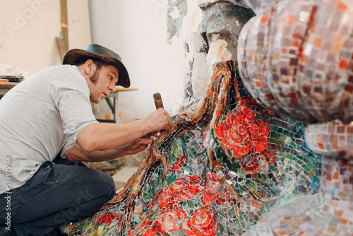 Man mosaics master in hat canadian making smalt glass mosaic panel. Male mosaicist artist at installation work photo