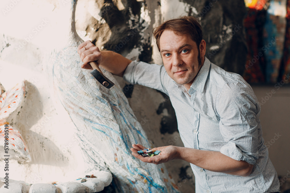 Φωτογραφία Craftsman male master portrait hold hammer and smalt glass pieces in arm hand for mosaic artwork in workshop