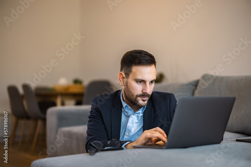 Focused man working over the laptop, sitting in the living room, elegantly dressed.