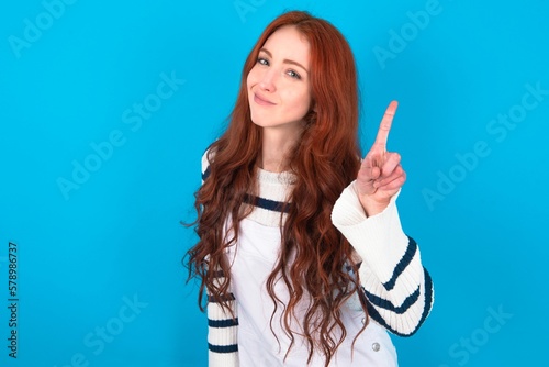 No sign gesture. Closeup portrait unhappy young caucasian woman wearing overalls over blue background raising fore finger up saying no. Negative emotions facial expressions, feelings. photo