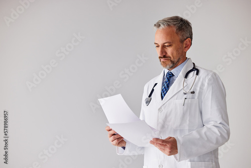 A senior doctor reading the results of his patient, standing with a stethoscope. photo