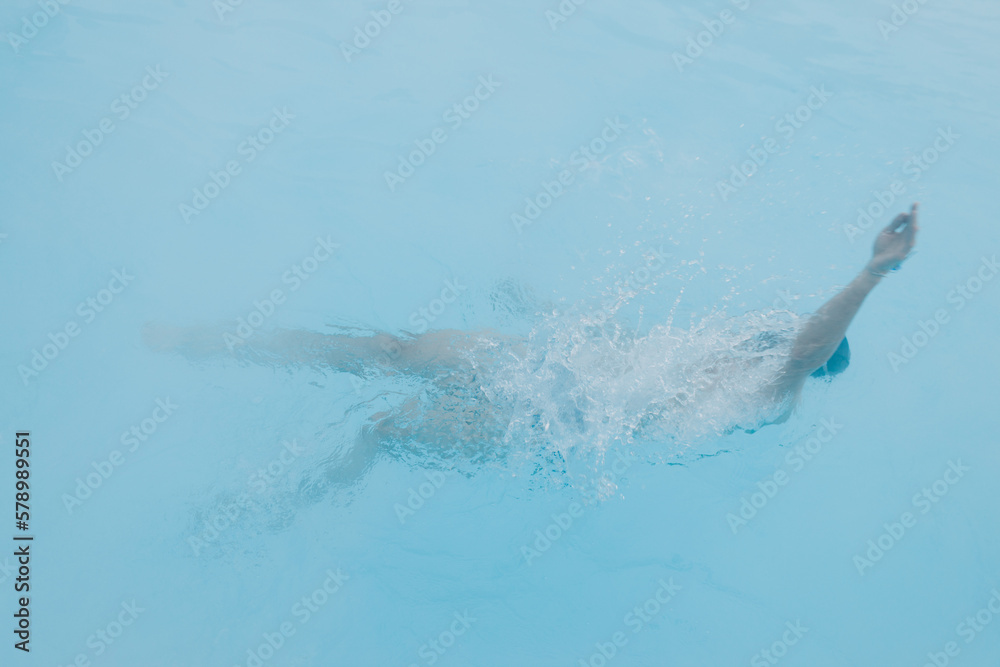 Naklejka premium Fit swimmer male training swim in open winter swimming pool with fog. Geothermal outdoor spa health concept.