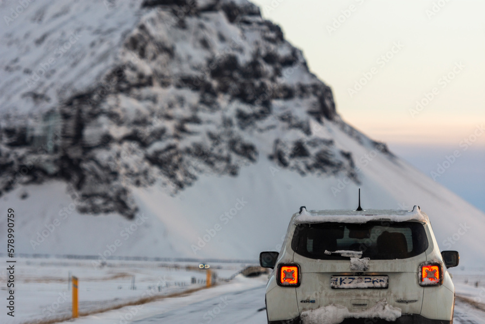 imagen de un coche por una carretera nevada con una montaña nevada de fondo y el cielo amaneciendo imagen de un coche por una carretera nevada con una montaña nevada de fondo y el cielo amaneciendo