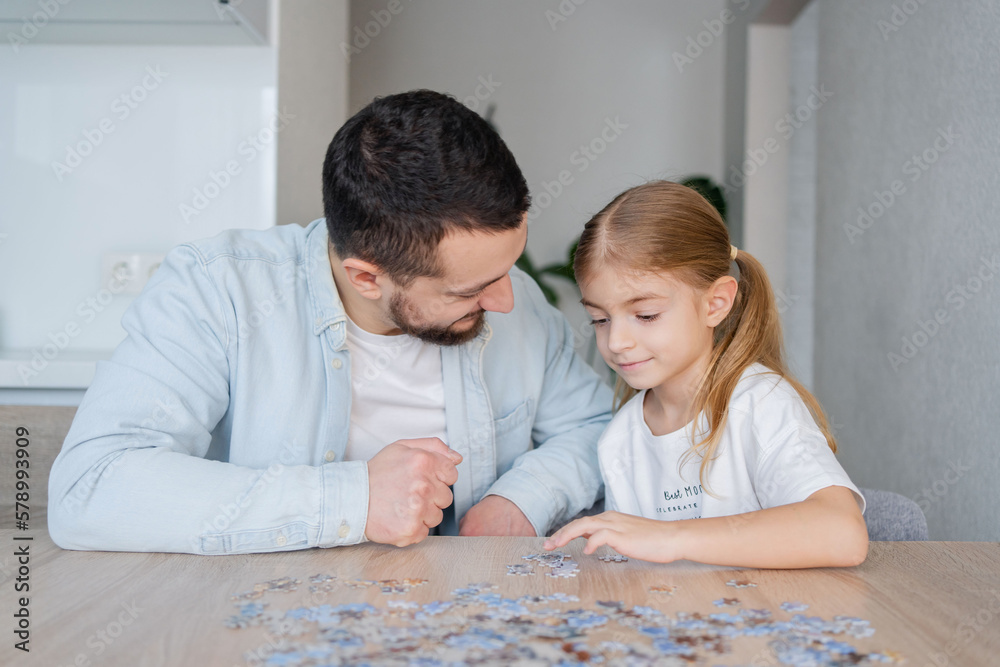 man playing puzzle with daughter at home.