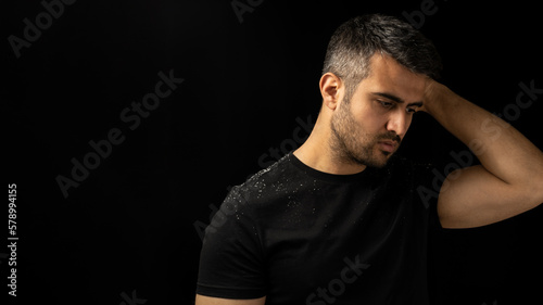 Close up low key portrait of man with dandruff or itchy hair problem. Concept of hair care,  dandruff and seborrheic dermatitis.