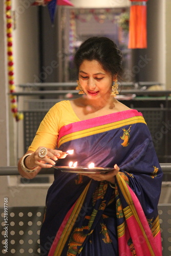 an indian woman in a traditional saari on occassion of Diwali festival with diya lamp in hand and arranging at door steps photo