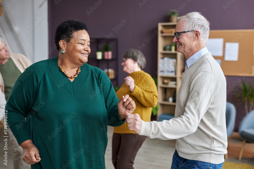 Fototapeta premium Waist up portrait of senior couple dancing in retirement home and enjoying group activities