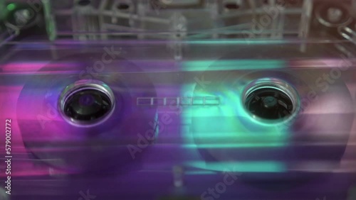 Spinning cassette tape in the cassette player, close-up, 80s, 90s style music concept, neon light colors. Synthwave, retrowave style.