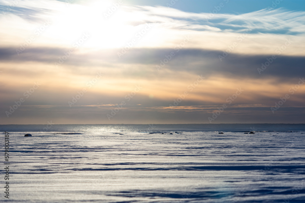 imagen de un paisaje nevado, con el mar de fondo y el cielo. nublado con el sol de fondo 