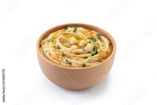 Chickpea hummus in a wooden bowl garnished with parsley, paprika and olive oil isolated on white background.  photo