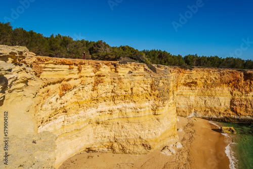 A man standing on the top of the cliffs of Corredoura beach, Algarve, Portugal photo