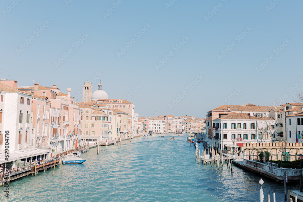 The great canal flows through Venice, taking its travelers with it. Everything shines in bright sunshine and the water shines turquoise.
