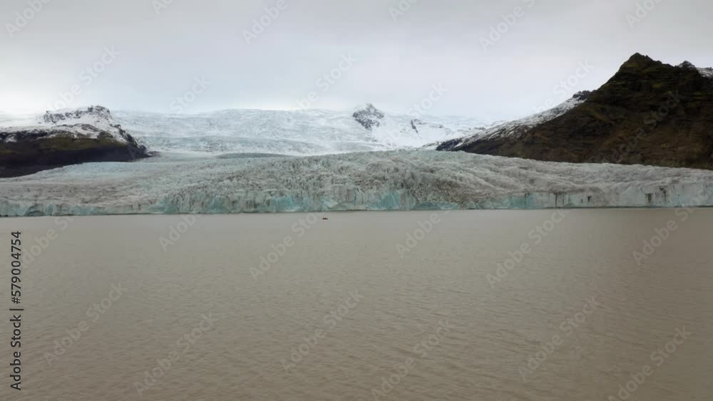Aerial: Flying towards a small boat with tourists near Fjallsarlon glacier in south iceland during an overcast day Aerial: Flying towards a small boat with tourists near Fjallsarlon glacier in south iceland during an overcast day