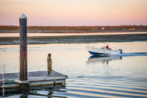 A woman on a pier looking toward a man on the boat, Faro, Algarve
