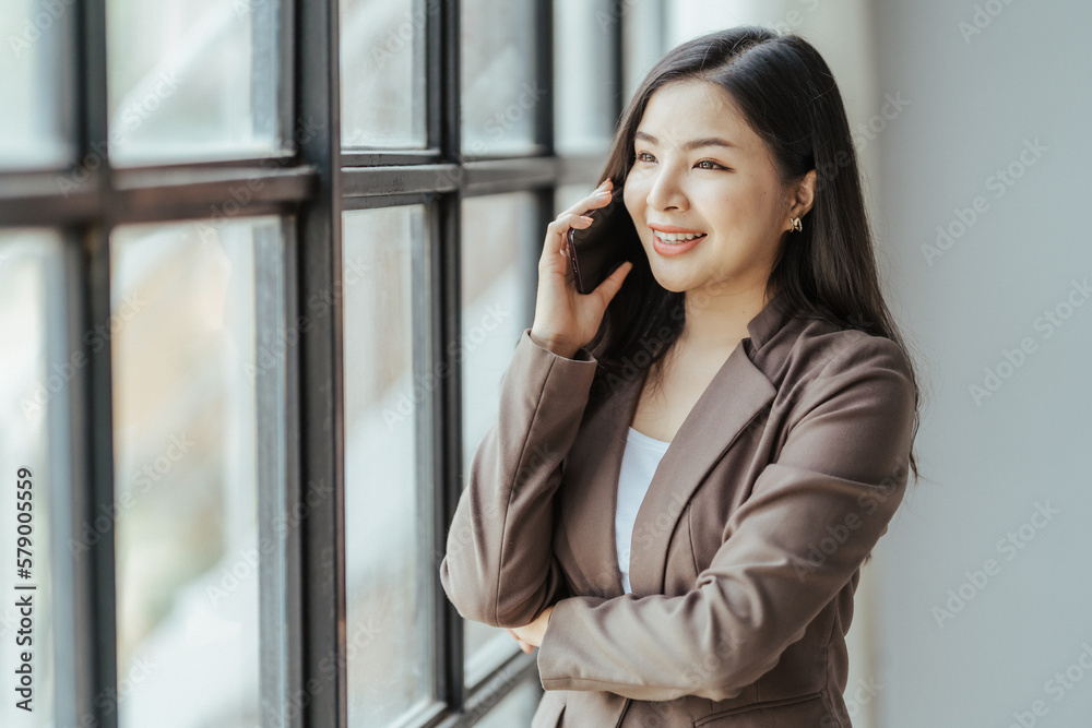 Asian businesswoman in formal suit in office happy and cheerful during using smartphone and working Asian businesswoman in formal suit in office happy and cheerful during using smartphone and working
