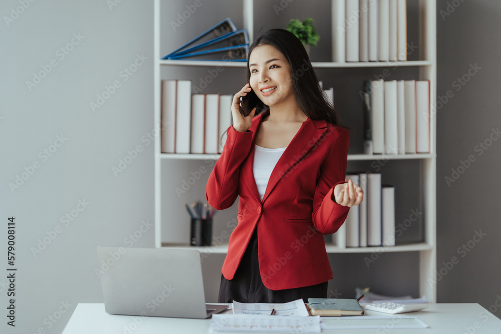 Asian businesswoman in formal suit in office happy and cheerful during using smartphone and working Asian businesswoman in formal suit in office happy and cheerful during using smartphone and working
