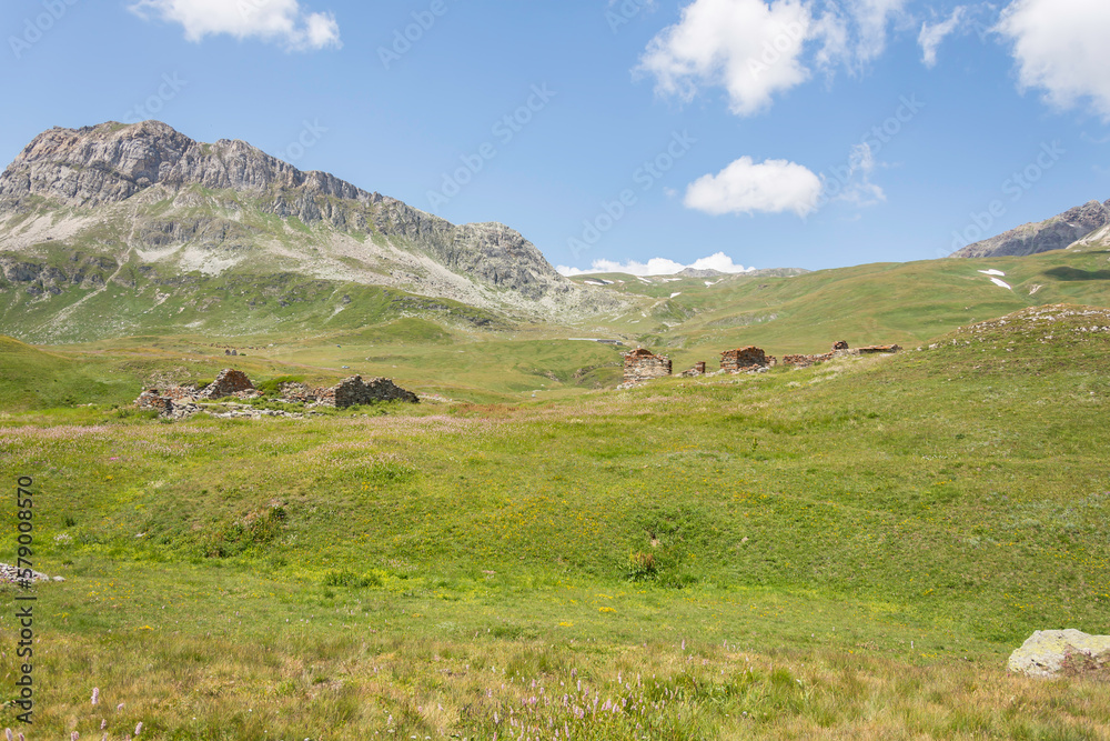 Sheepfolds in ruins in the middle of a green meadow and mountains in summer