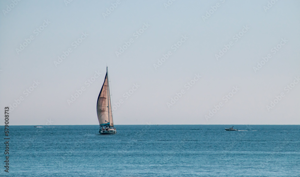 Velero navegando en el horizonte en Gallipoli, Italia. Yate con las velas desplegadas navengando en las aguas turquesas del mar Jónico. - obrazy, fototapety, plakaty 