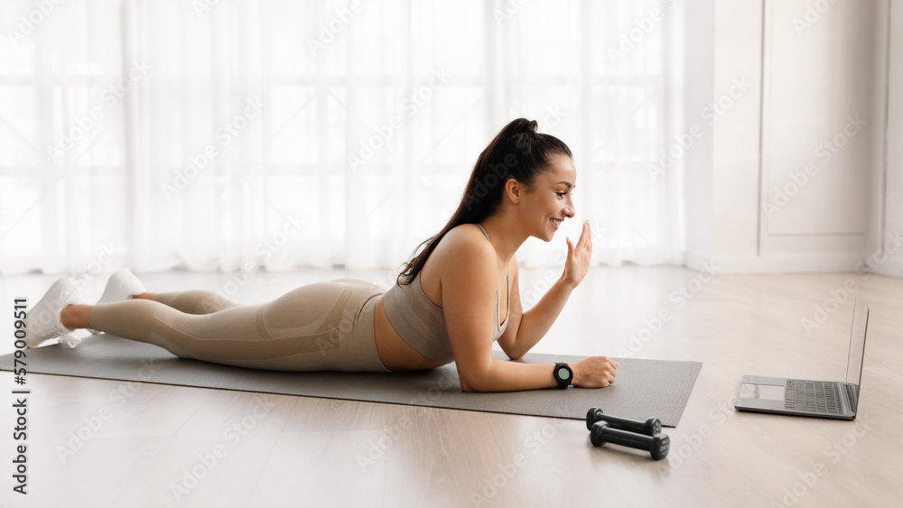 Fit woman doing yoga with fitness coach, waving at laptop Fit woman doing yoga with fitness coach, waving at laptop