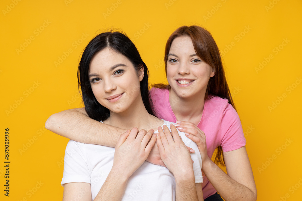 Two beautiful young women, sisters - twins on yellow background Two beautiful young women, sisters - twins on yellow background