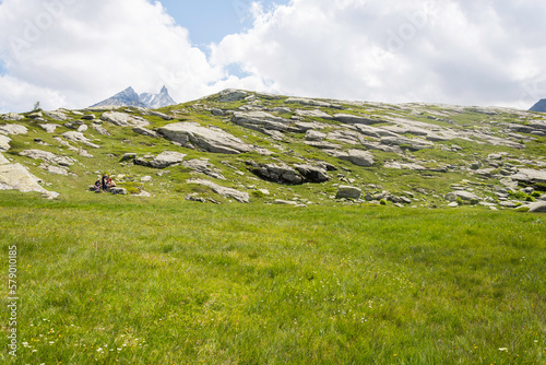 A group of people is taking a break in a green meadow before hiking again to the to the Mount Cenis Lake during summer. photo