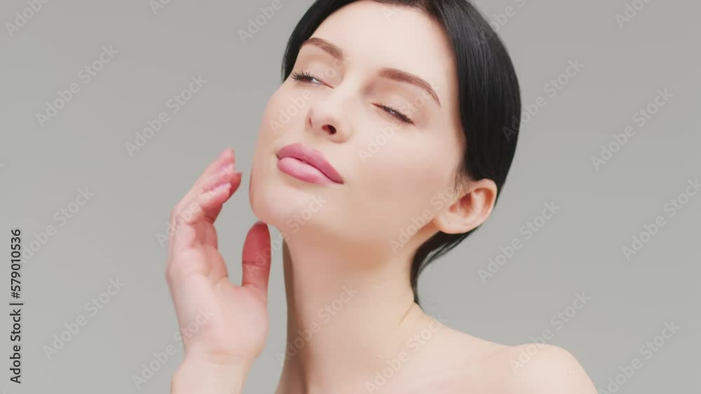 A slender young beautiful caucasian woman with dark hair turns to the left, touching her jawline and smiling broadly at the camera against the background. Moisturizer ad
A slender young beautiful caucasian woman with dark hair turns to the left, touching her jawline and smiling broadly at the camera against the background. Moisturizer ad